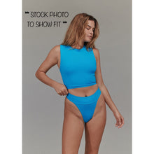 Model wearing Acacia Mateo bikini bottom in a similar style, front view, showing high-cut cheeky fit.

