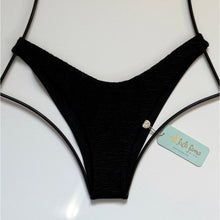 Black textured high-leg Brazilian bikini bottom by Luli Fama with gold charm detail, displayed flat with original tags.