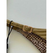 Close-up of Acacia Swimwear Ralphy Bikini Bottom in Palm, showing matte logo hardware engraved with “ACACIA” and adjustable side strap detail over ribbed tan fabric with subtle animal-print lining beneath.