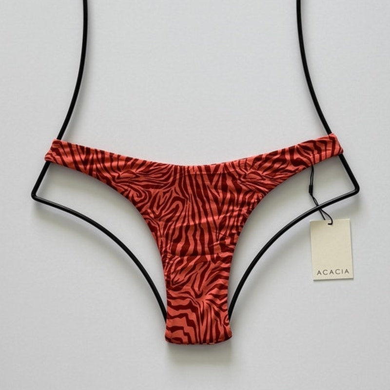 Front flat lay of Acacia Bodywear Oslo Lining Bikini Bottom in Neon Mares with coral zebra-inspired print.