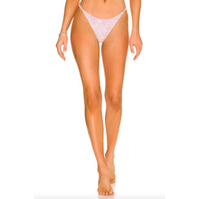 Model wearing Acacia Neema Bikini Bottom in Dahlai floral print, front view showing slim straps and cheeky fit