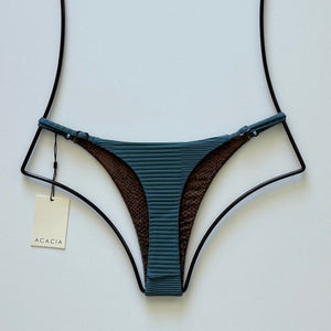 Front flat lay of Acacia Swimwear Ralphy Dual Ribbed Bikini Bottom in Horizon – teal-blue ribbed texture with Acacia hangtag visible.