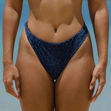 Model wearing Acacia Swimwear Brazil bikini bottom in Blue Amur print at the beach.
