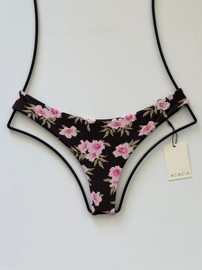Acacia Swimwear Ho’okipa bikini bottom in Floret print, front view. Dark brown base with pink floral design, cheeky Brazilian cut, minimal coverage.