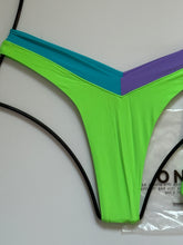 Close-up of OneOne Swimwear Jesse Bikini Bottom in Nissi Neon Green with aqua and lilac V-cut waistband detail, flat lay on white background.