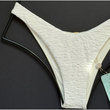 Detailed view of the textured fabric and high-leg cut on the ivory Luli Fama Buleria bikini bottom.