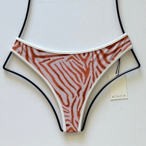 Flat lay of Acacia Swimwear Flynn Piped Bikini Bottom in Sabi print with rust zebra stripes and white piping.