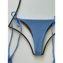 Flat lay close-up: Detailed shot of ribbed texture and inner animal print lining on Acacia Swimwear Lauie bikini bottom in Seine blue.