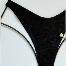 Detailed view of the textured fabric and high-leg cut on the black Luli Fama Buleria bikini bottom.
